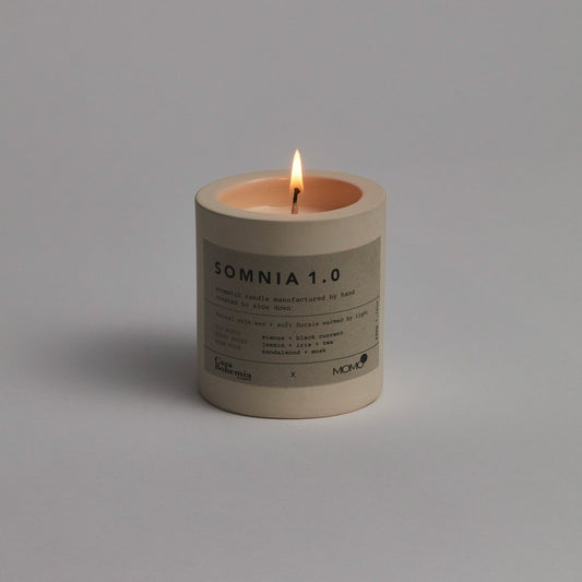 Somnia 1.0 geurkaars van Momo Cotton met brandende vlam op grijze achtergrond