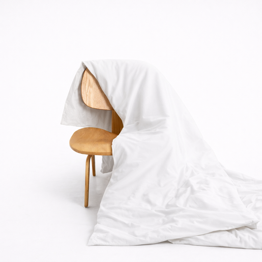 White bamboo duvet cover draped over wooden chair, showing soft fabric texture and hidden button closure design