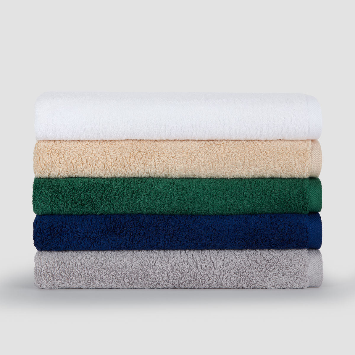Stack of five folded bamboo towels in white, beige, green, navy, and gray colors displayed against a light background.
