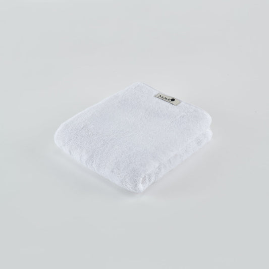 Witte bamboe handdoek van Momo Cotton gevouwen op lichte achtergrond met zichtbaar merklabel