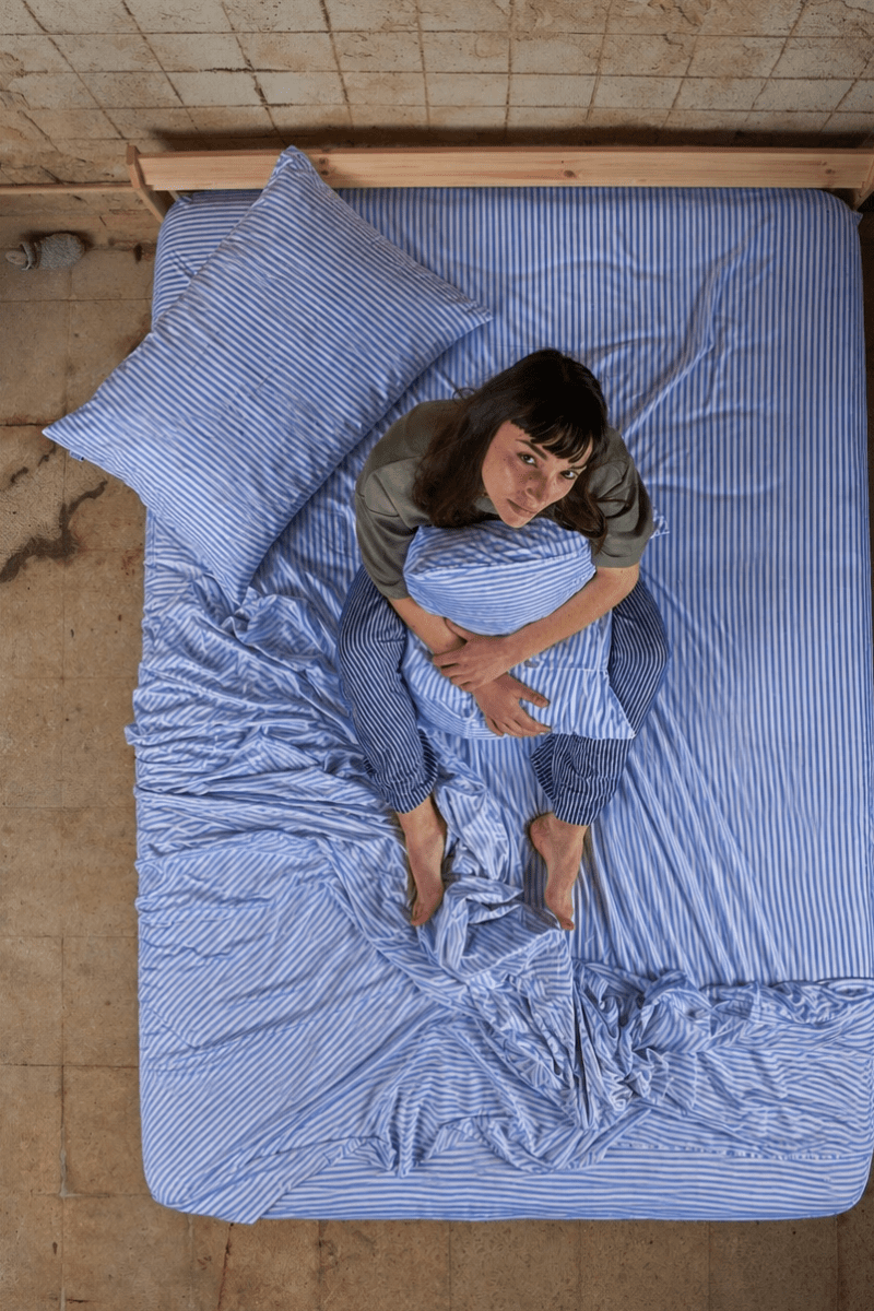 Vrouw liggend op bed met blauwe gestreept bamboe katoenen beddengoed set van bovenaf