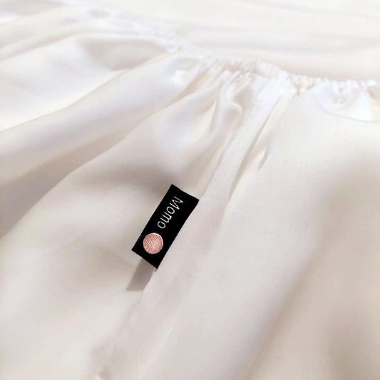 White bamboo fitted sheet with momo-cotton brand label on folded fabric surface
