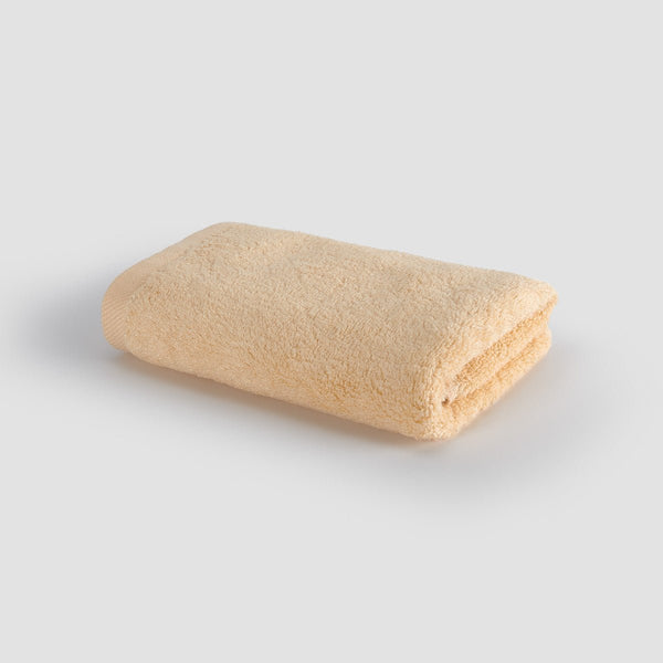 Beige gevouwen handdoek op witte achtergrond, bovenaanzicht