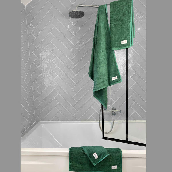 Groen Wabi-sabi badmat in moderne douche met visgraatpatroon tegels en zwarte glazen douchewand