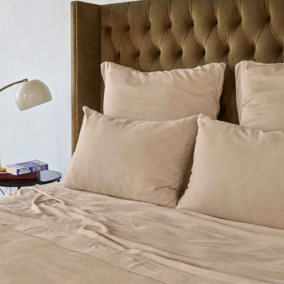 Cremekleurig bovenlakenop bed met bruine gestoffeerde hoofdeinde en beige kussens