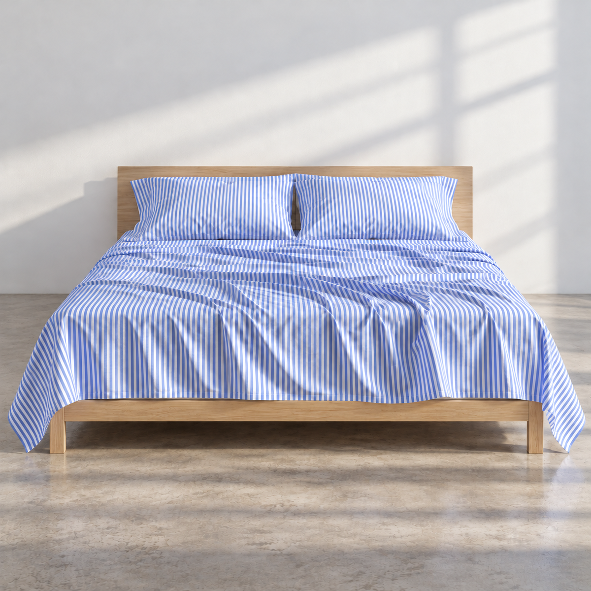 Blauw beddengoed met streeppatroon op licht houten bed in lichte ruimte