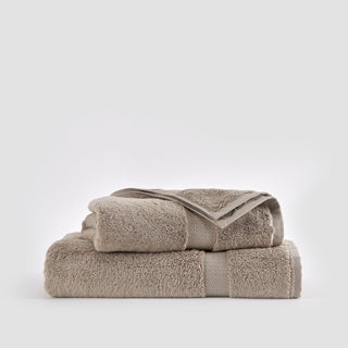 Beige bamboe handdoekenset gestapeld met washandje, handdoek en badhanddoek op witte achtergrond