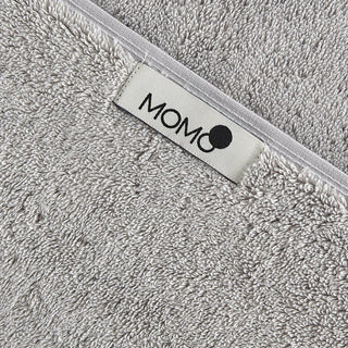 Grijze bamboe handdoek met momo-cotton merklabel op witte rand, close-up van zachte textuur