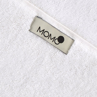 MOMO merklogo op close-up van wit bamboe handdoekstof detail
