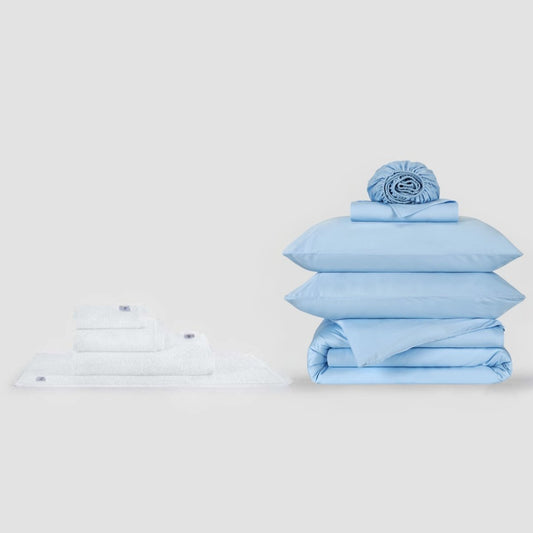 Blauw-wit beddengoed set met kussens en gevouwen lakens op witte achtergrond
