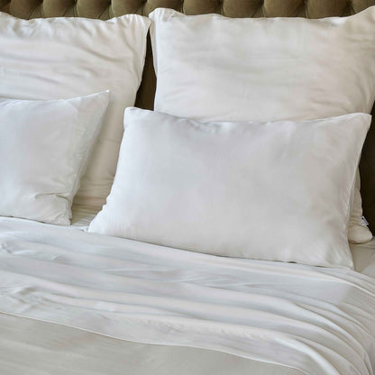 Wit beddengoed op bed met kussens en beige gewatteerd hoofdeinde