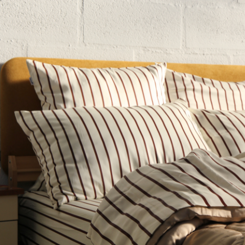Bamboe beddengoed met strepen en bijpassende kussens op lichthout bedframe