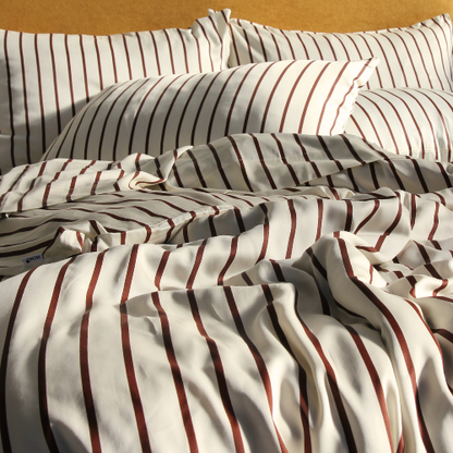 Complete bamboe beddengoed set met rood gestreept patroon, netjes gevouwen kussenslopen en lakens op het bed