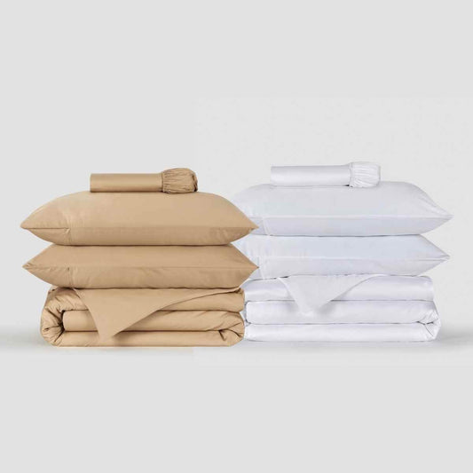 Beige en witte beddengoedsets netjes gestapeld, met kussens en dekbedovertrekken van Momo Cotton