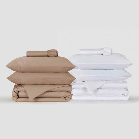 Beige en witte dekbedovertreksets gestapeld met opgeklapte beddengoed met kussens en lakens van Momo Cotton