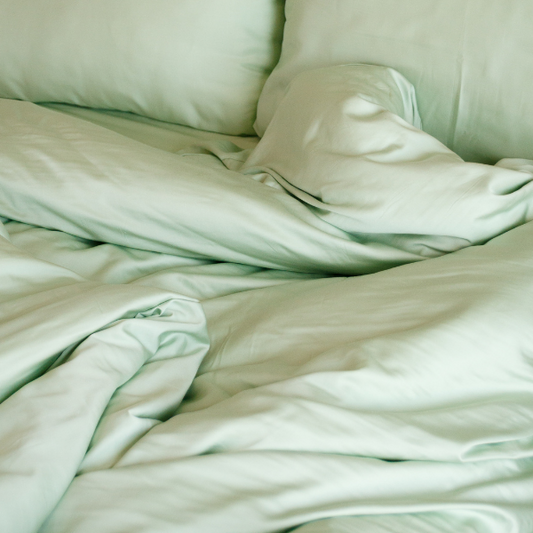 Jogo de cama em bambu verde sálvia exibido na cama mostrando lençol ajustável, lençol de cima, fronha e capa de edredão