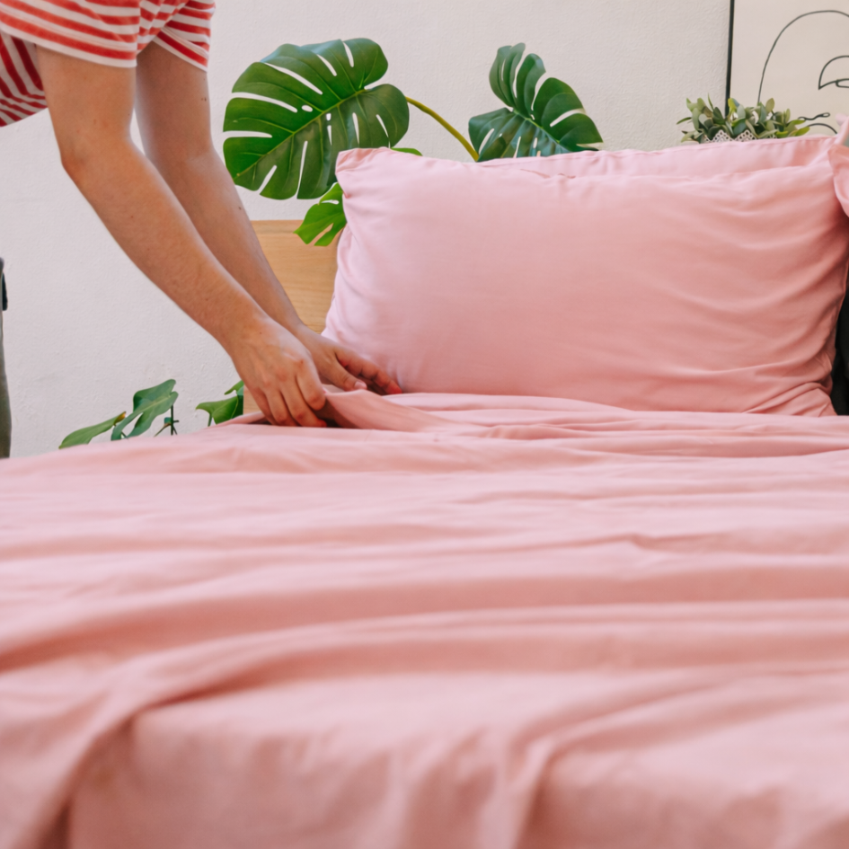 Hands holding pink bamboeweefsel, highlighting its lightweight, silky texture.
