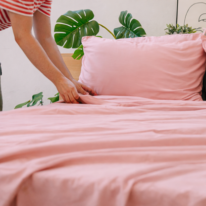 Hands holding pink bamboeweefsel, highlighting its lightweight, silky texture.